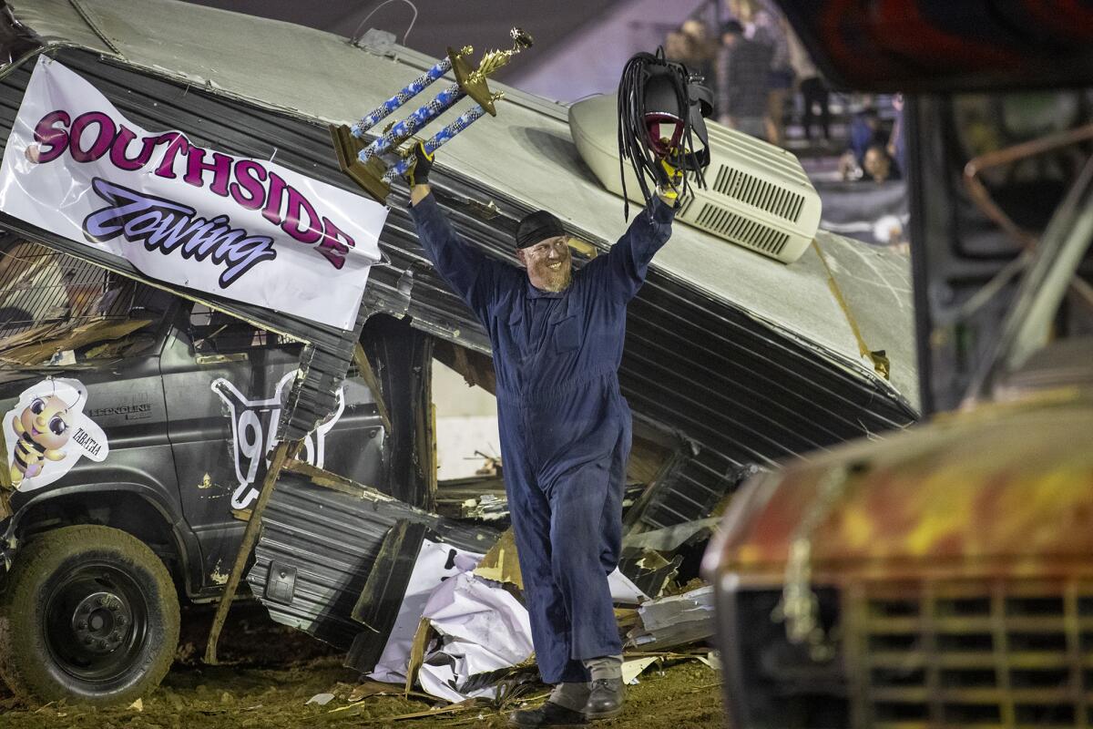 Driver Tony Axton raises his hands in victory following the Motorhome Madness demolition derby.