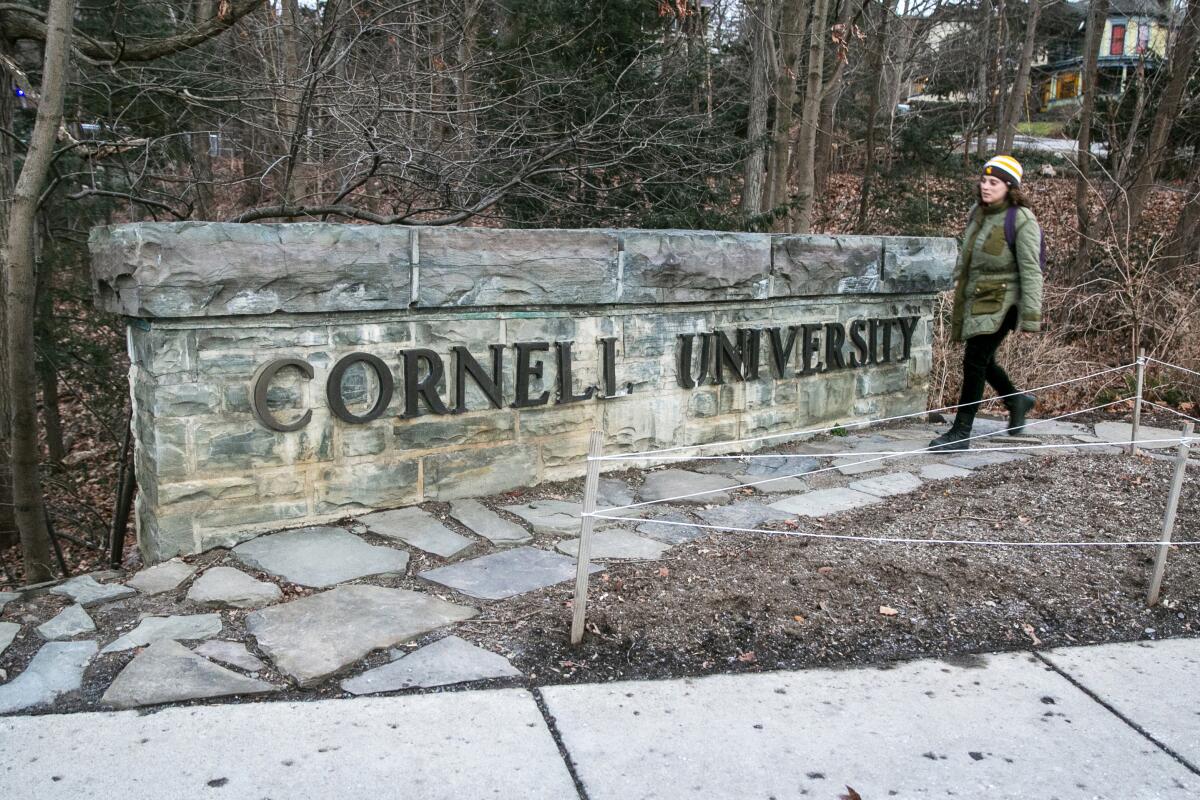 A woman walks by a Cornell University sign.