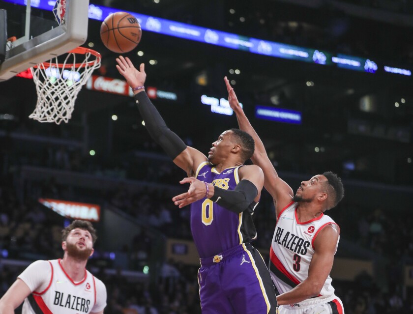 Lakers point guard Russell Westbrook drives to the basket past Portland Trail Blazers guard Jusuf Nurkic and guard CJ McCollum.