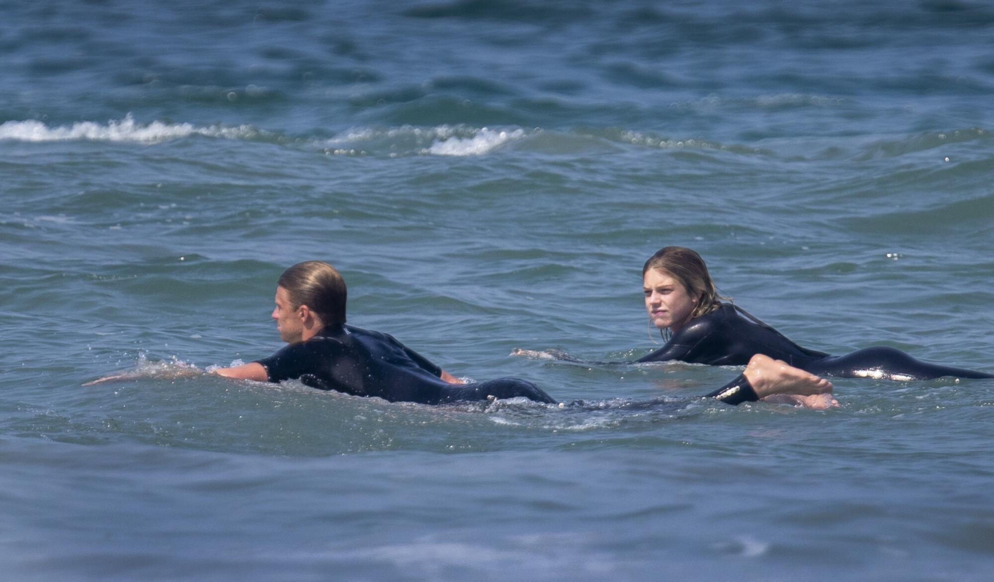 Kolohe Andino, left, paddles out at Bolsa Chica State Beach in Huntington Beach.