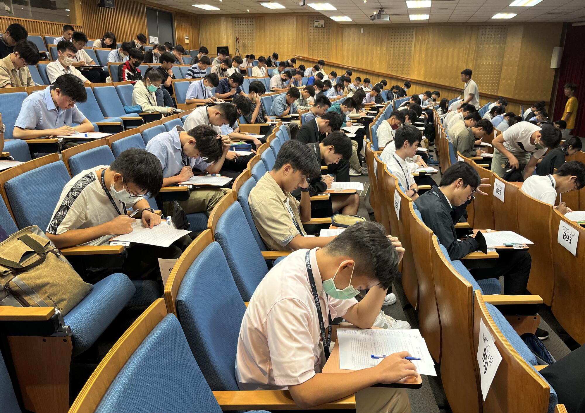 Rows of test takers seated in an auditorium-style room