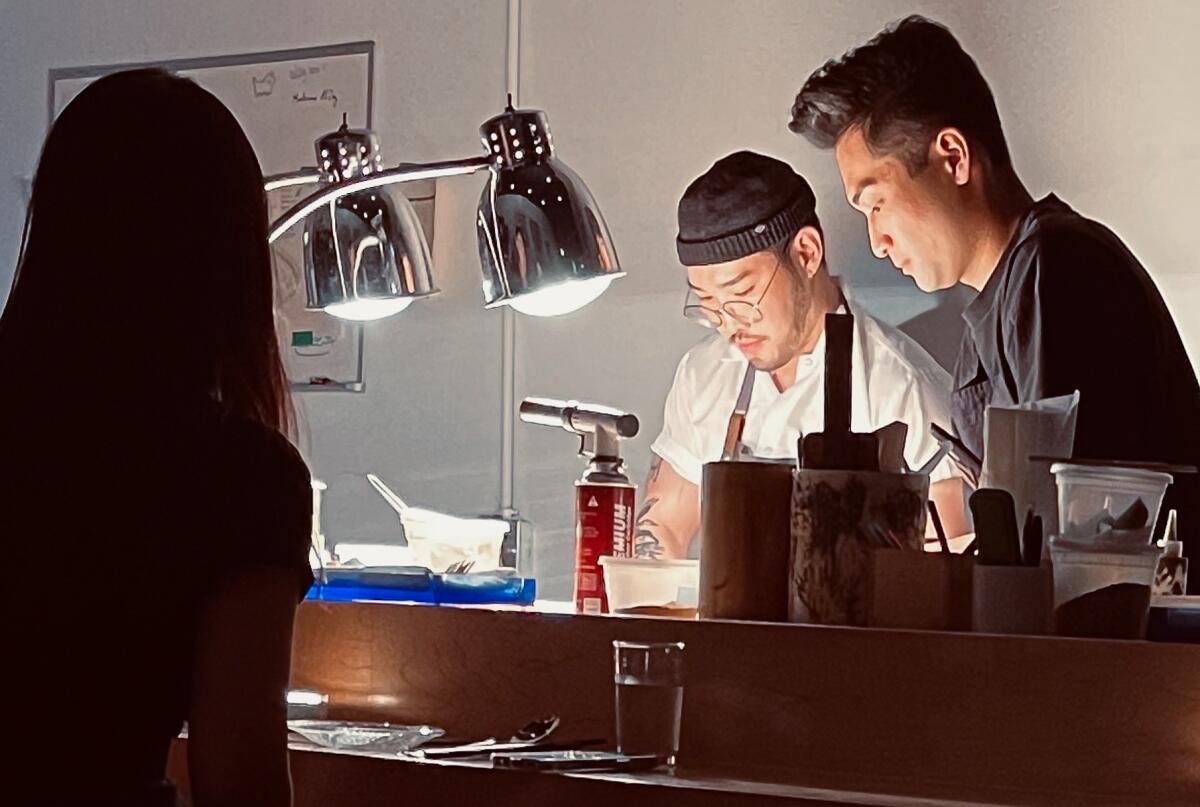 Two chefs prepare food in the light of strong lamps.