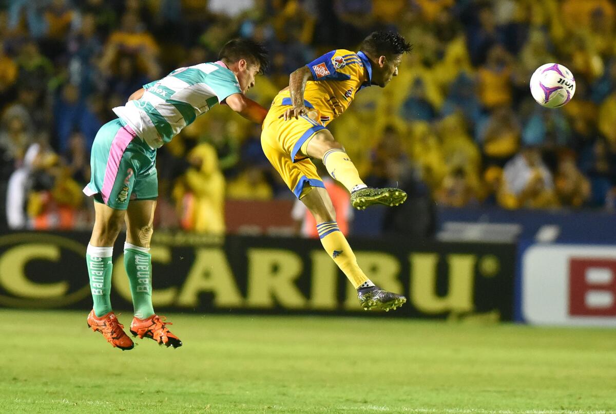 Javier Aquino (d) Tigres disputa el balón contra José Abella (i) del Santos, en el estadio Universitario de Monterrey, México.