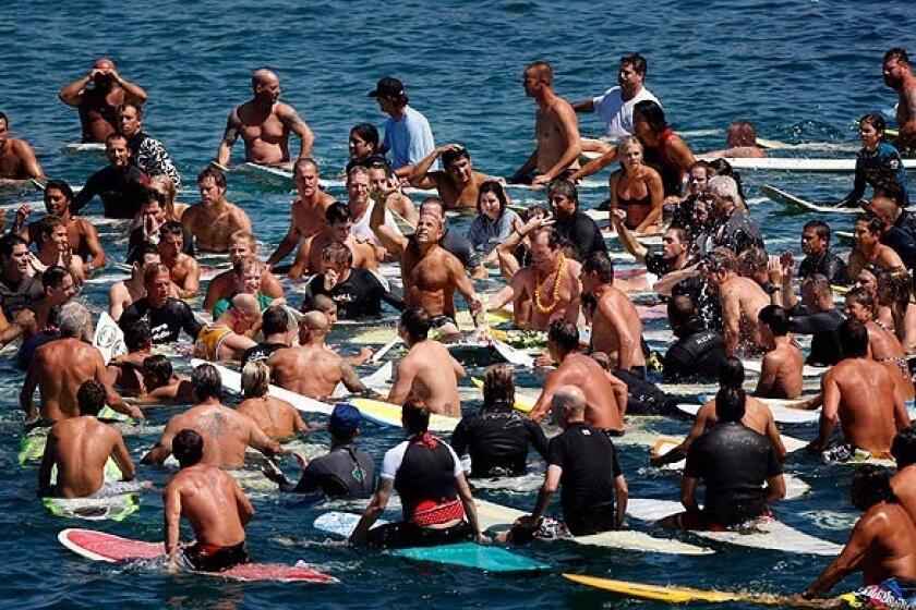 Family and friends gather next to the Huntington Beach pier for a Hawaiian-style paddle out memorial for surfer John Kissel, 43, of Costa Mesa who died Aug. 29 in a cliff-diving accident at Lake Havasu.
