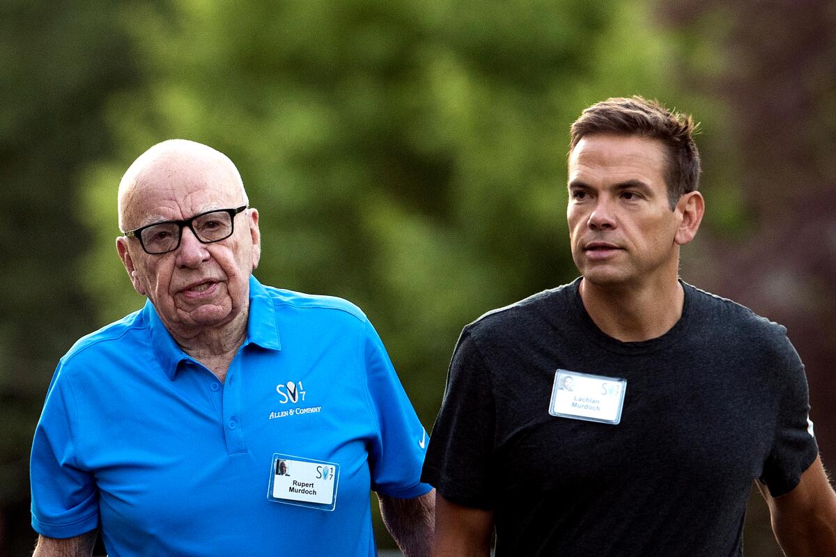 Rupert Murdoch, in a blue polo, and Lachlan Murdoch, in a dark shirt, stand side by side.