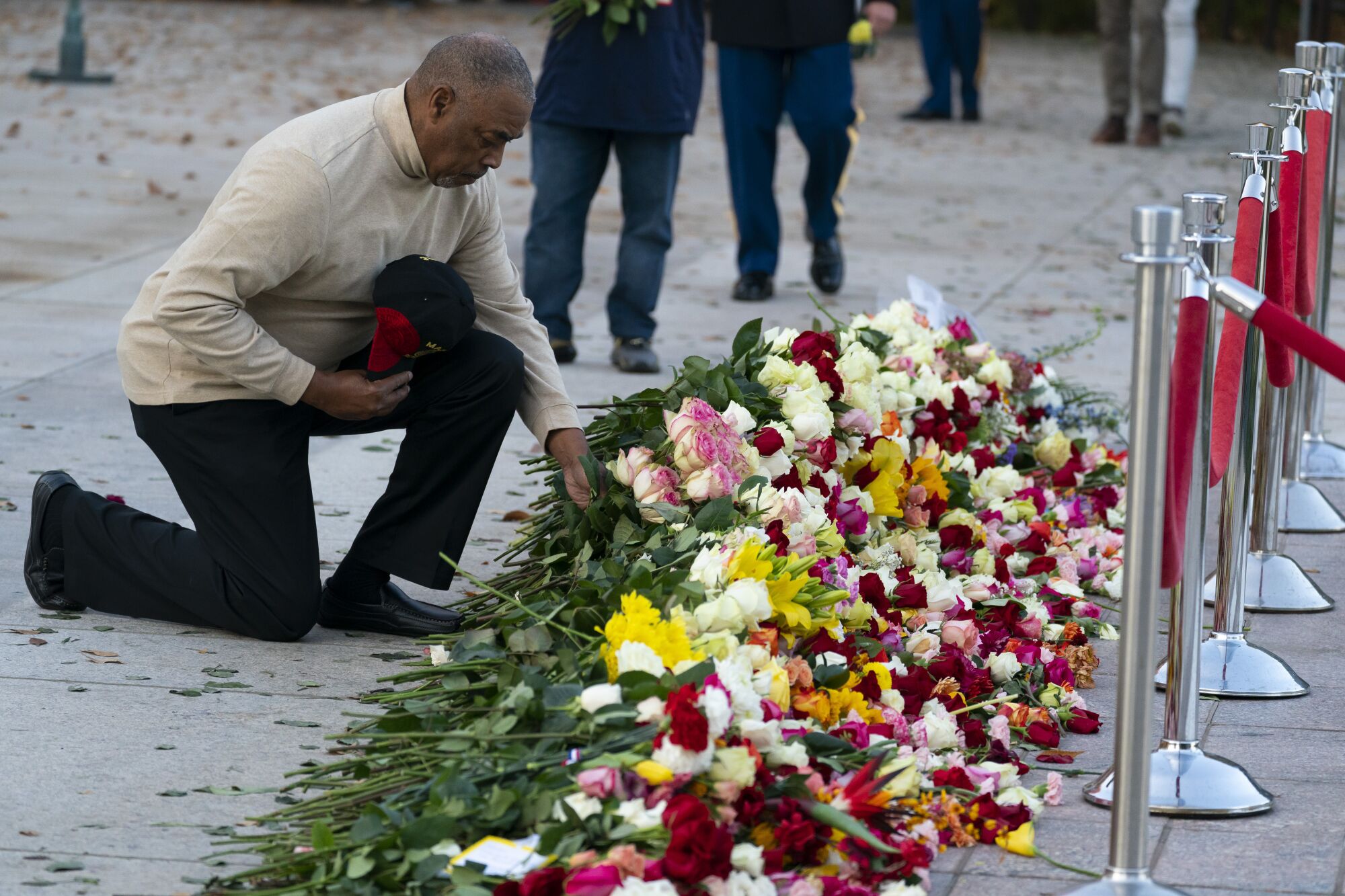 A man kneels to place flowers