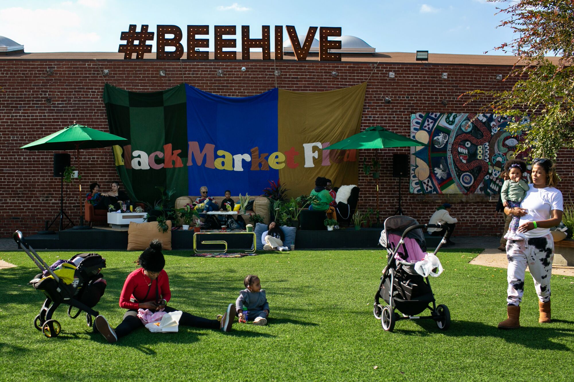 People sit on the lawn outside a building with signs that say
