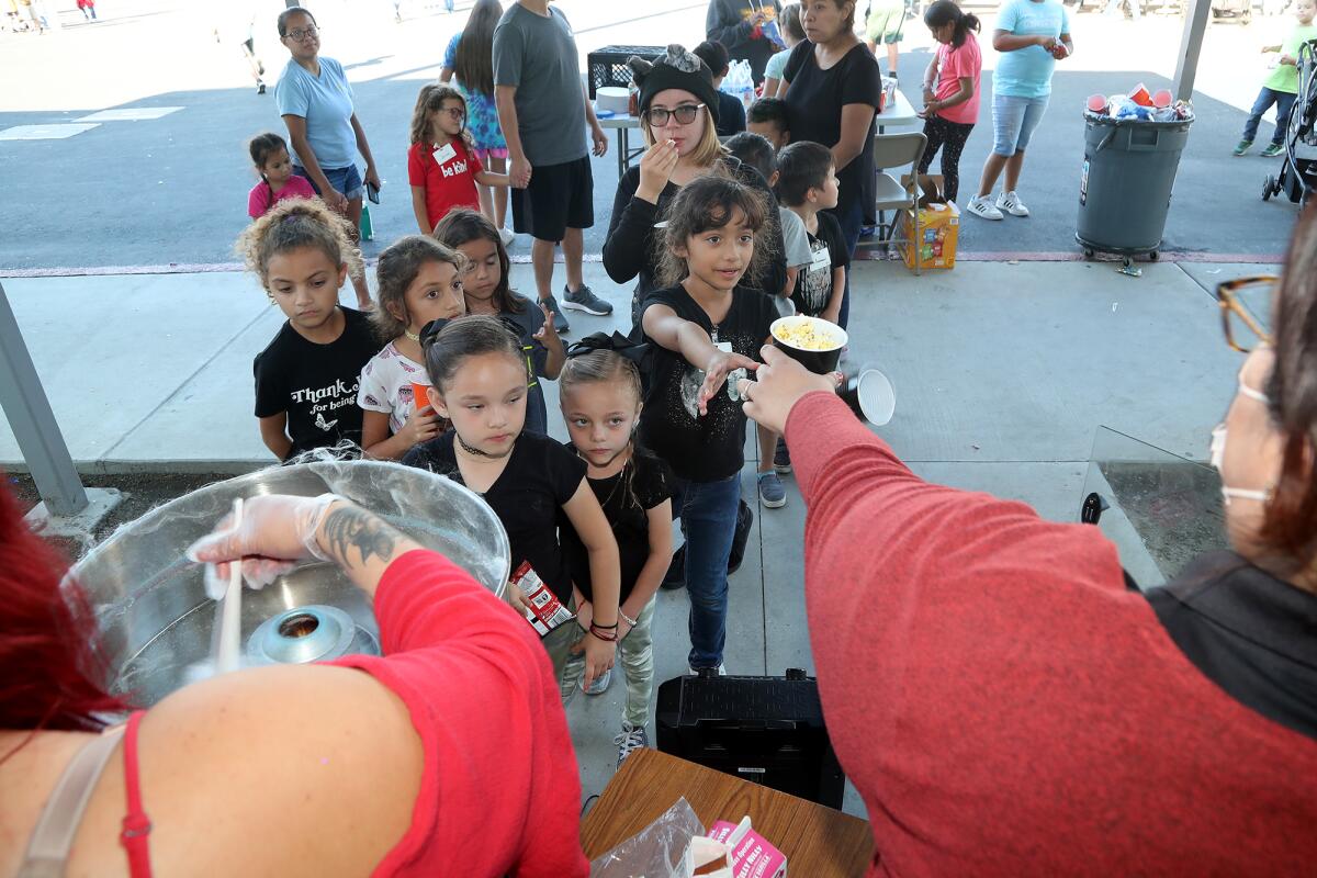 Students line up for cotton candy and popcorn during the "Lights On Afterschool" event at Sonora Elementary on Friday.