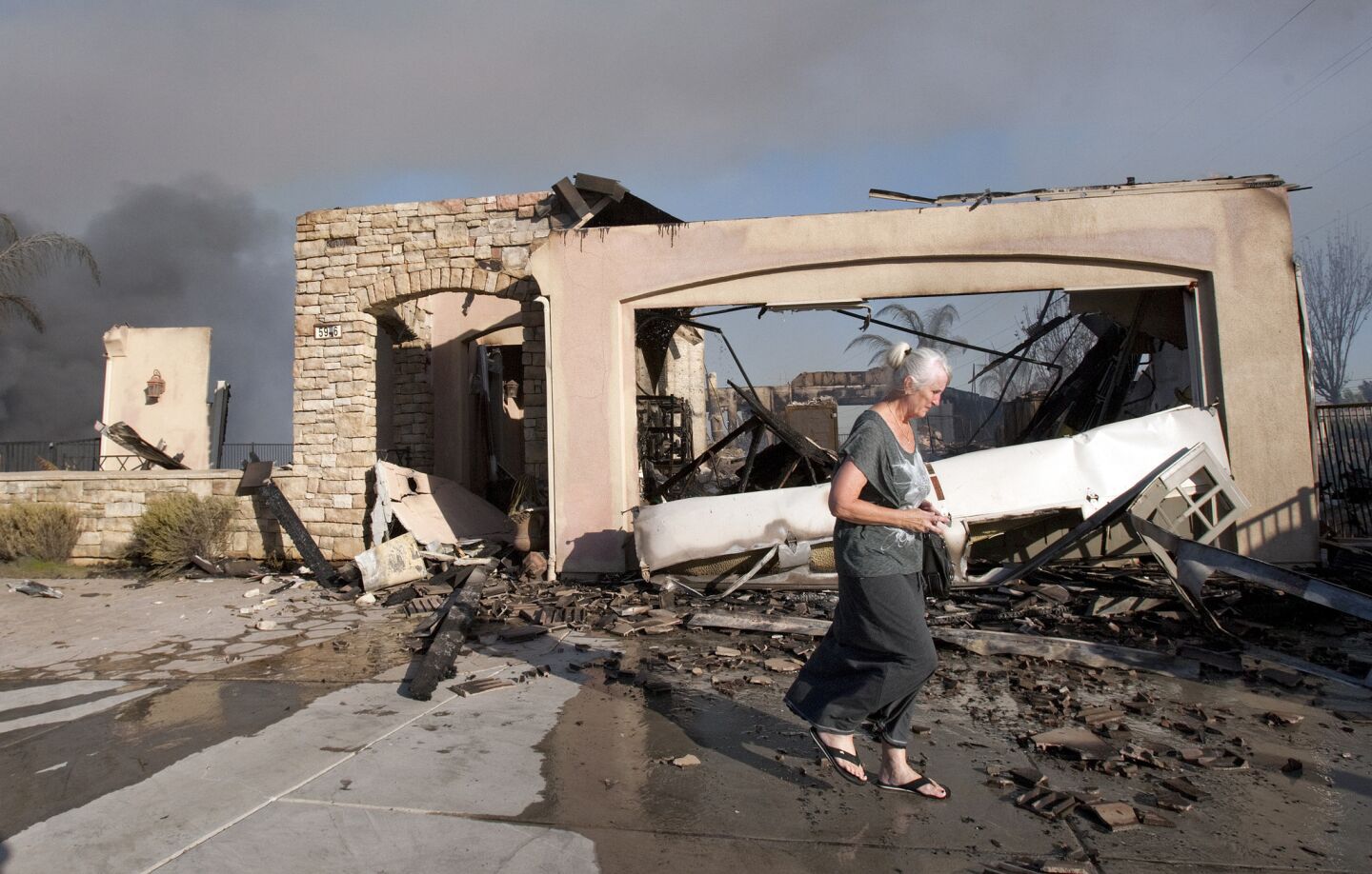 Sophie Payne walks past what is left of her home on Black Rail Road after it was destroyed in the Poinsettia wildfire on May 14, 2014 in Carlsbad, Calif.