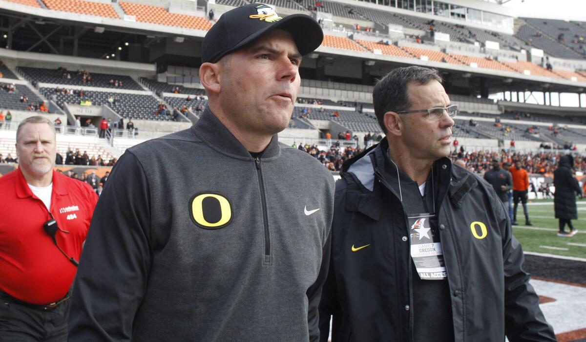 Mark Helfrich, center, comes onto the field for an interview before a game against Oregon State on Saturday.