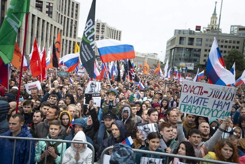 A crowd of protesters in Russia, some holding flags or signs.