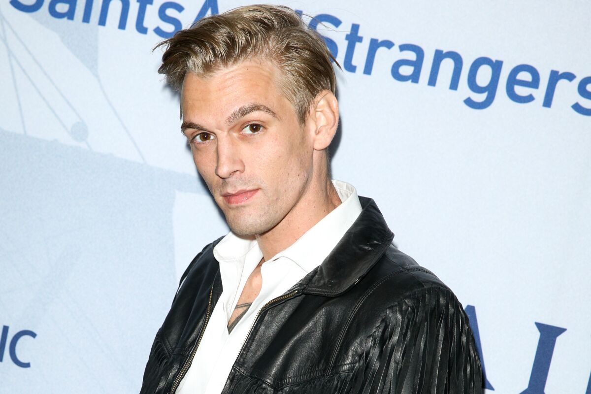 A fresh-faced Aaron Carter poses in a white button-up shirt and black leather blazer