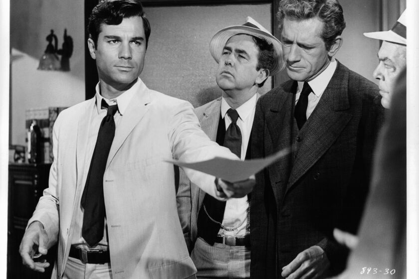 George Maharis offers documents as unidentified men watch in a scene from the film 'A Covenant With Death', 1967. (Photo by Warner Brothers/Getty Images)