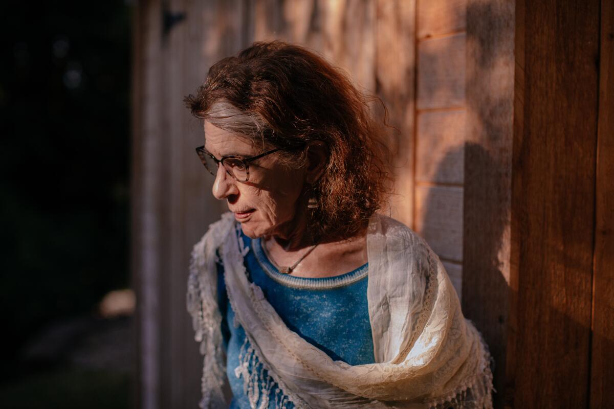 A woman in glasses and a shawl looks pensive.