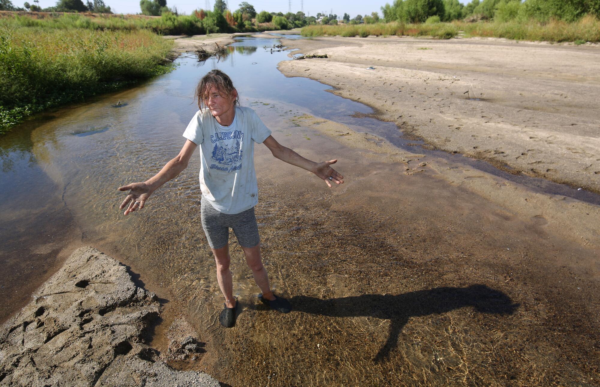 A woman speaks while standing in a shallow stretch of the dwindling Kern River. 