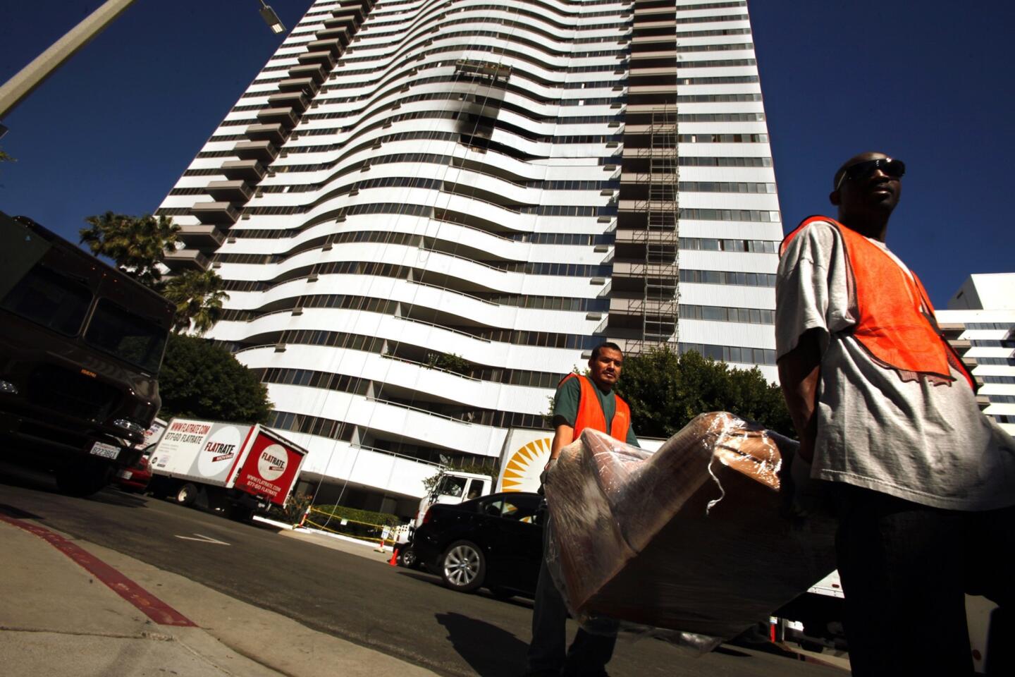 Movers transport furniture from the Barrington Plaza Apartments. Some residents have been moving out of the apartments after a fire in the high-rise on Oct. 18. Many occupants have realized that the building is not equipped with a sprinkler system.