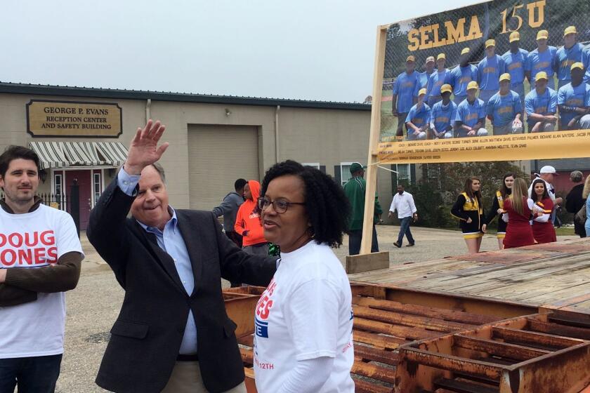 Doug Jones, second from left, the Democratic candidate for U.S. Senate, waves to a supporter as he walks in a Christmas parade, Saturday, Dec, 2, 2017, in Selma, Ala. Jones is trying to shore up support among black voters in his U.S. Senate race against Republican Roy Moore by appealing for an end to the divisiveness that has long been part of the state's politics. (AP Photo/Jeff Amy)