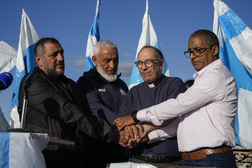 From left to right, Rabbi Haim Bendao, President of Olympique de Marseille’s South Winners supporter group Rachid Zeroual, Father Olivier Spinosa, and Imam Hassan Rajii, hold hands during a minute of silence held at an interfaith peace rally, organized with the help of Marseille's South Winners, outside Marseille's Notre-Deame de la Gard basilica, southern France, Tuesday, Oct. 24, 2023. French President Emmanuel Macron visited Israel on Tuesday, where he reaffirmed calls to prevent the war from expanding into Lebanon and the wider Arab world, and called for a "decisive" political process with the Palestinians for a viable peace. (AP Photo/Daniel Cole)