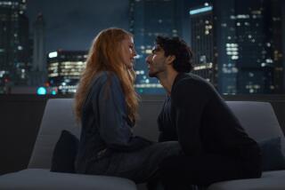 Blake Lively and Justin Baldoni leaning in for a kiss on a couch on a rooftop overlooking a city skyline