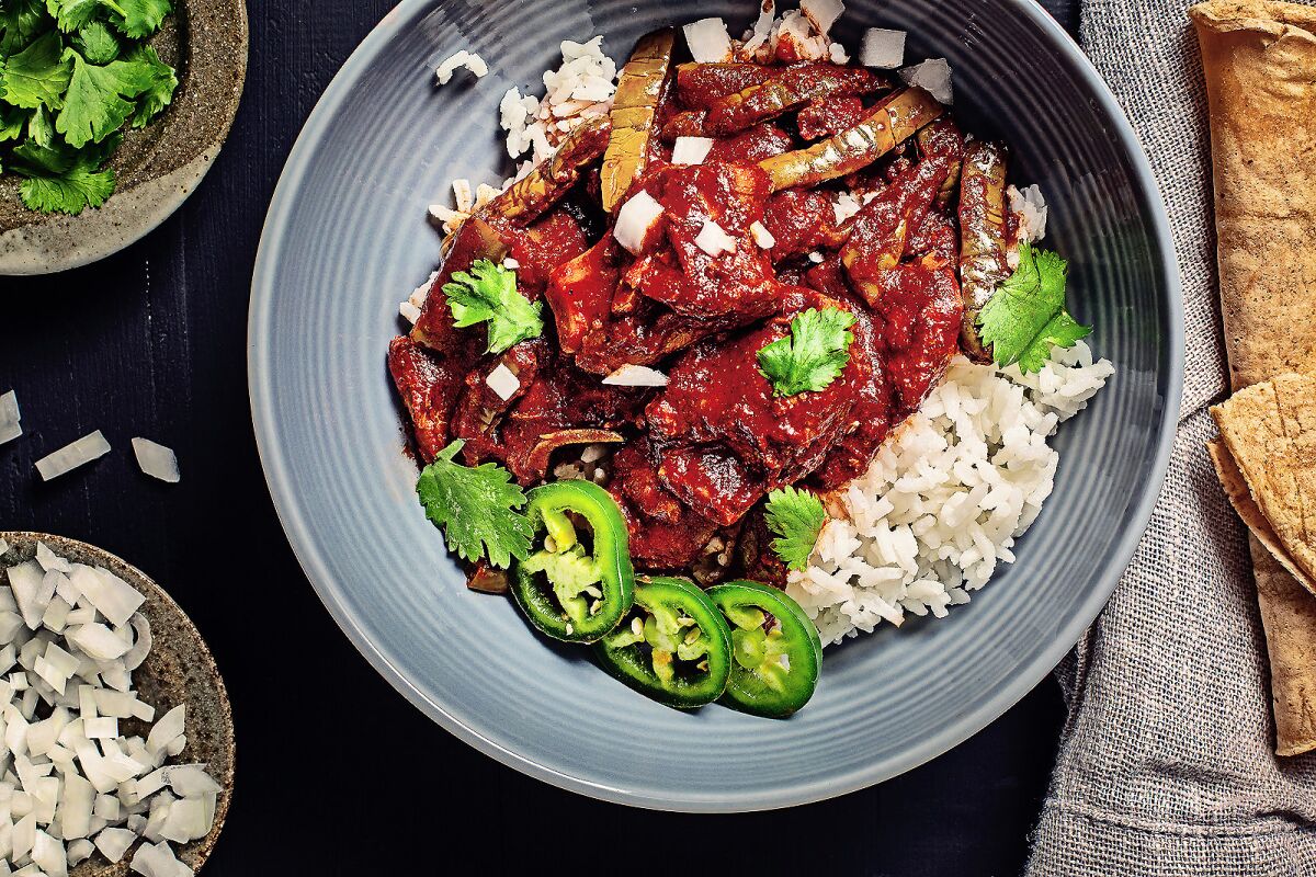 A bowl of pork rib tips and lemony nopales smothered in guajillo chile sauce over rice.