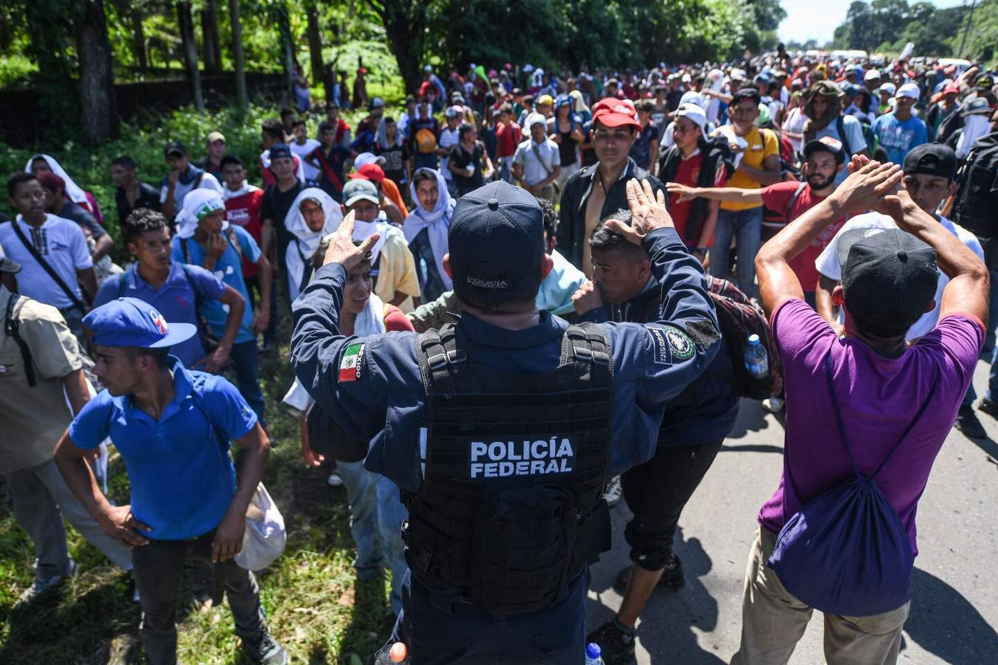 A Mexican federal police officer speaks with Honduran migrants heading in a caravan to the U.S. on the road linking Ciudad Hidalgo and Tapachula, Mexico.