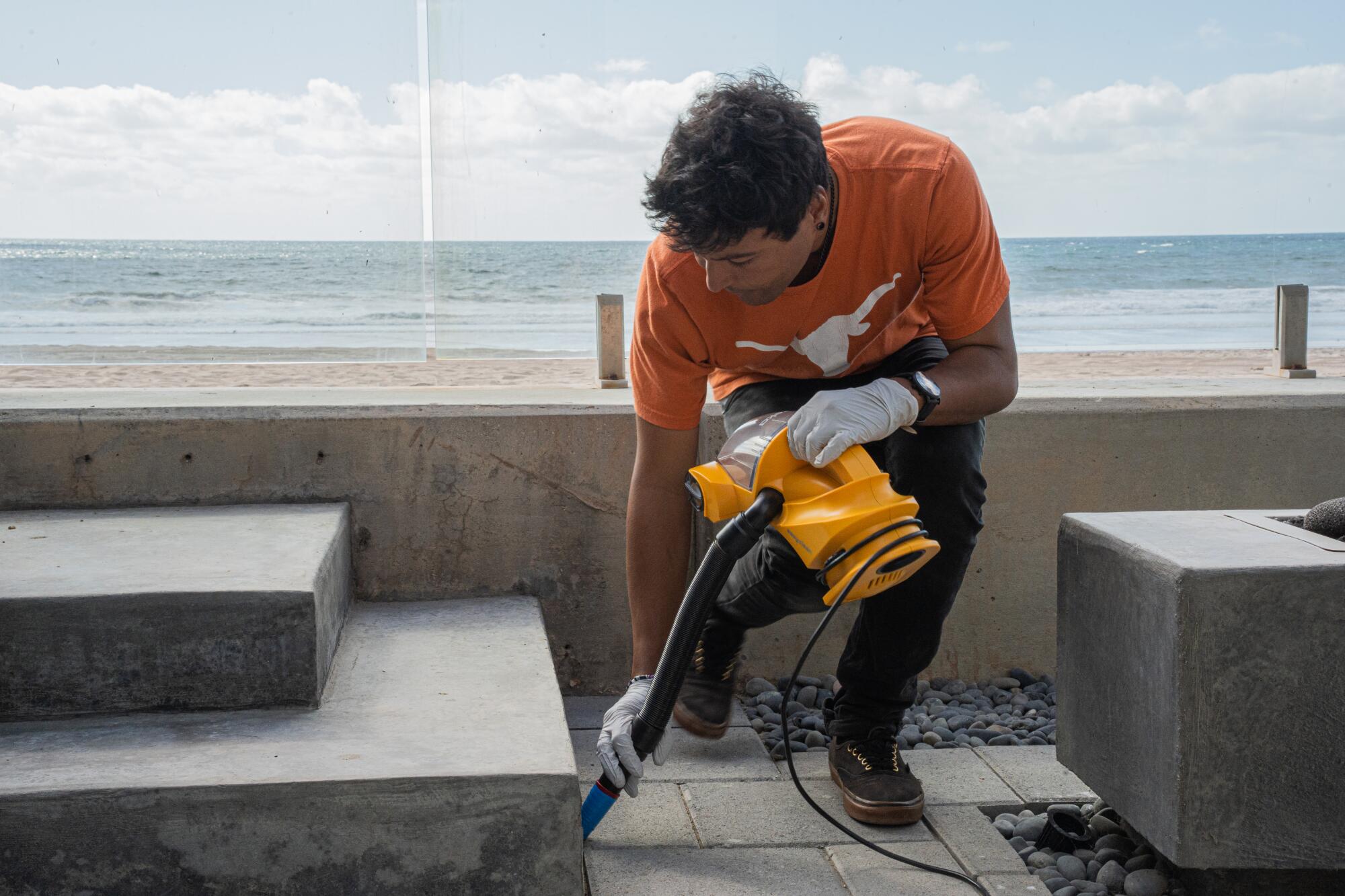 A researcher vacuums the crevices of a patio to take dust samples.