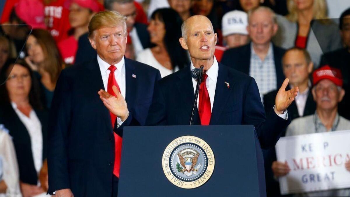 President Trump stands behind Florida Gov. and Senate candidate Rick Scott at a campaign rally in Pensacola on Nov. 3.