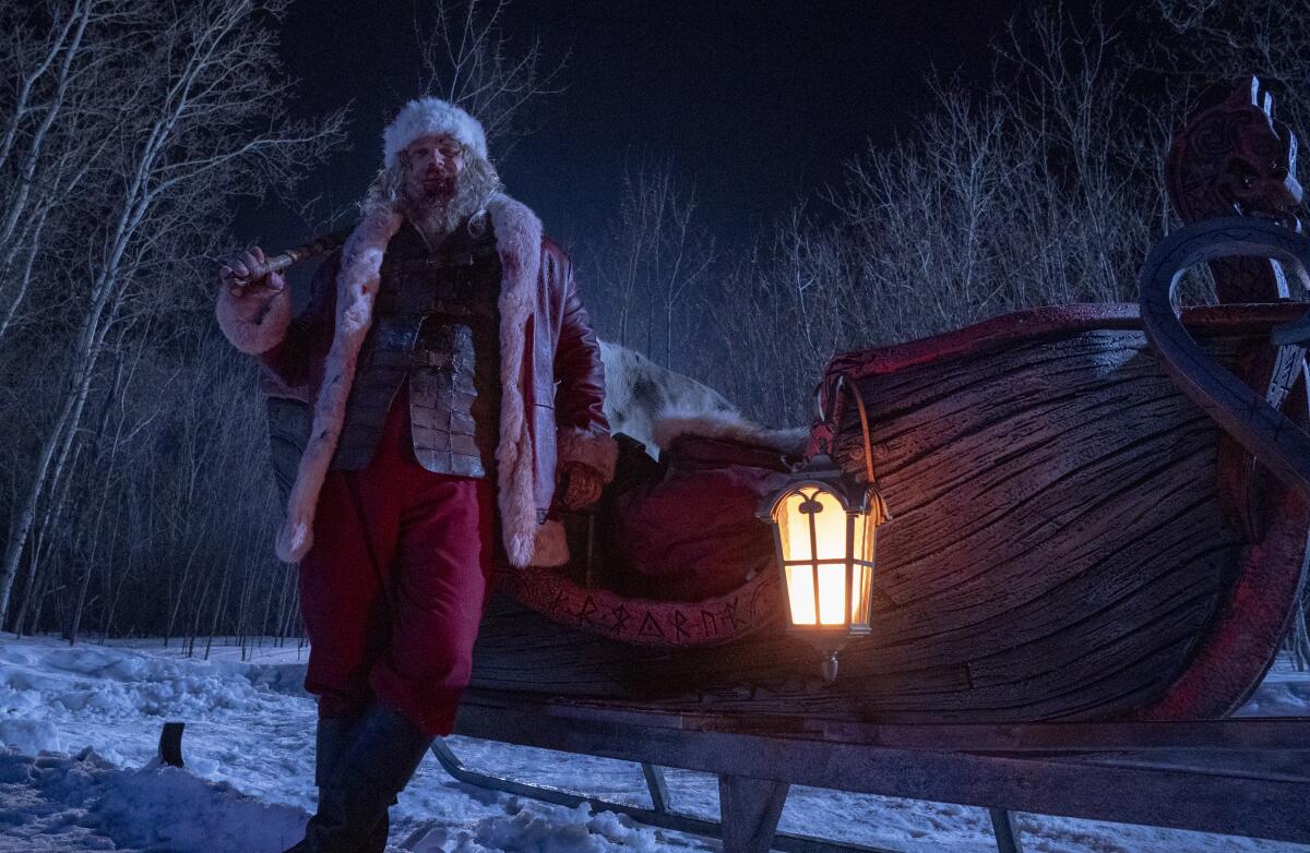 A bedraggled Santa Claus leans against his sleigh.