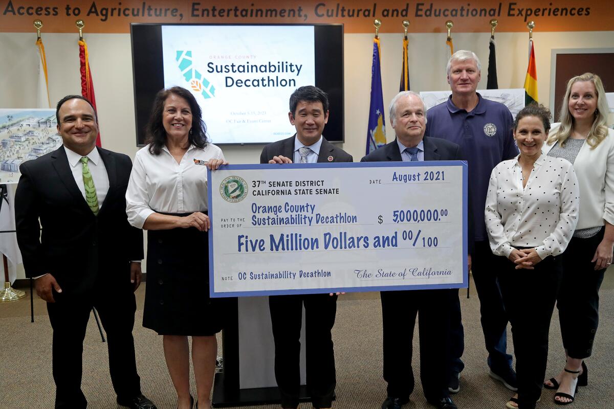 Sen. Dave Min presents a $5-million check at a news conference.