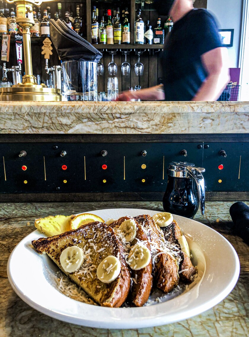 A plate of French toast with banana slices on a restaurant table.