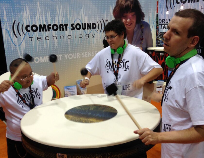 Three students from Teri Campus for Life in Oceanside demonstrate new-technology drums at the Remo booth at the 2015 NAMM Show in Anaheim.