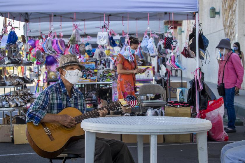WESTMINSTER, CA - AUGUST 05: Keith Tran, of Santa Ana, plays guitar while wearing a mask to protect himself and others from contracting COVID-19 at the Asian Garden Mall, which is closed to indoor shopping but some shops are open outdoors under tents on Wednesday, Aug. 5, 2020 in Westminster, CA. In Little Saigon in Orange County, the low number of coronavirus cases and deaths is the result of cultural habits and "consistent" behavior, according to experts and immigrants themselves. They cite three reasons: The Vietnamese are "more disciplined" in following CDC guidelines based on deep reverence for the medical profession. They already are used to wearing masks in the homeland to avoid spreading common illnesses and to protect users from dust and fumes while zipping around on mopeds, a primary method of transportation. And within extended families, people tend to appoint a representative who is the only person to venture outside buying groceries, running errands or attending to urgent matters. Dr. Quynh Kieu and her assistants - she is a pediatrician who led a major project testing about 2,000 Vietnamese American patients from May to July, resulting in just 8 positive cases. (Allen J. Schaben / Los Angeles Times)