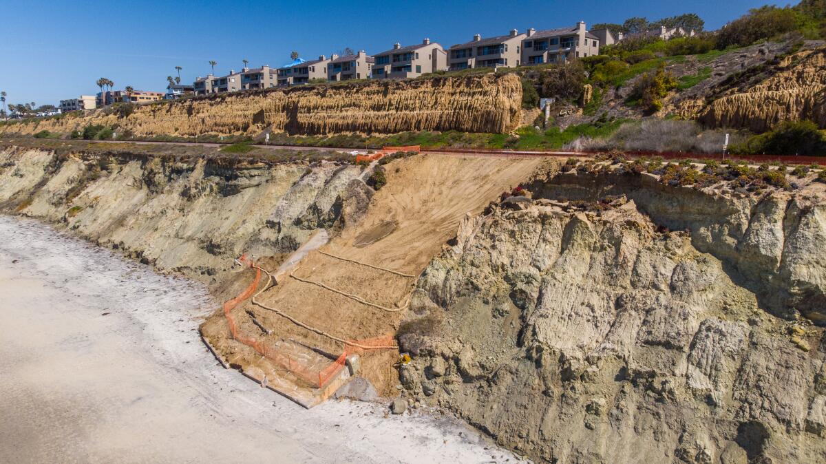 Netting covers a flattened portion of coastal bluffs alongside a beach.