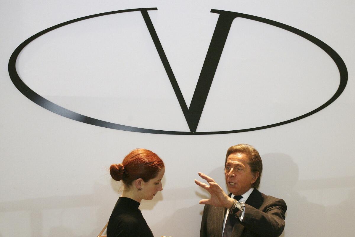 En esta imagen de archivo, el diseñador de moda italiano Valentino (derecha), bajo el logo de su marca, 