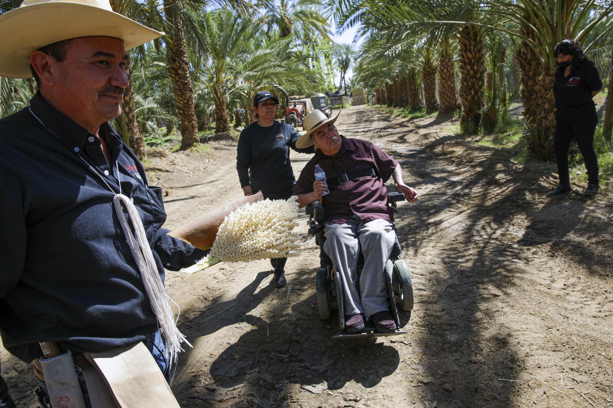 Alvaro Bautista, left, holding medjool male date palm flower, is shown with family members.