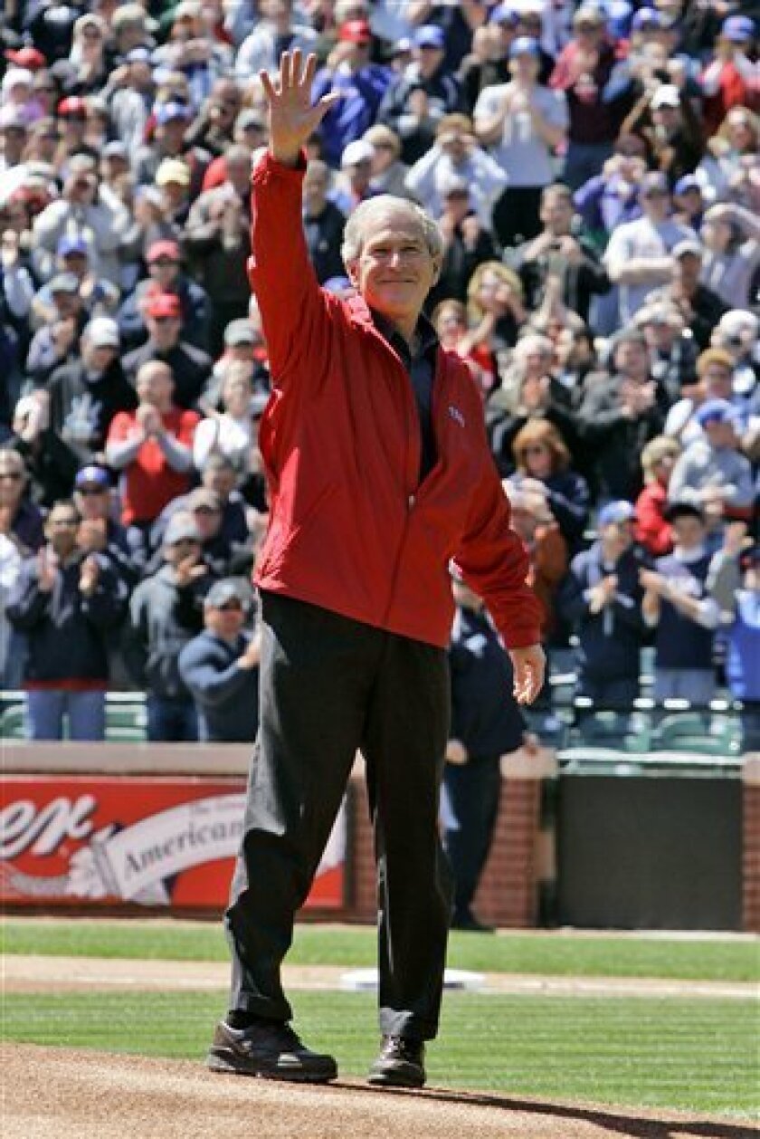 Former President George W. Bush waves before throwing out the season opening first pitch before the baseball game between the Cleveland Indians and Texas Rangers in Arlington, Texas, Monday, April 6, 2009. (AP Photo/Tony Gutierrez)