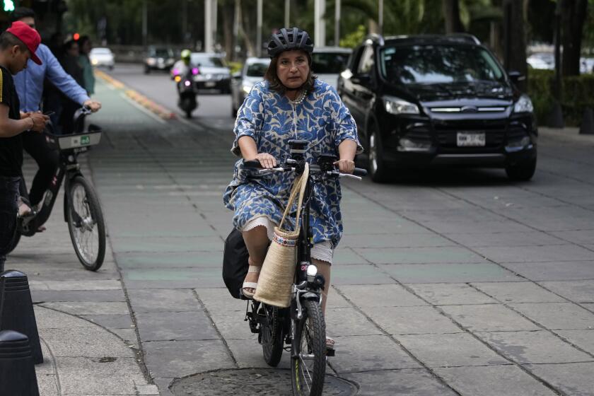 FILE - Senator Xochitl Galvez, an opposition presidential hopeful, rides a bike upon her arrival to a hotel for the announcement of the opposition presidential candidates in Mexico City, Wednesday, Aug. 9, 2023. The main opposition parties declared on Wednesday, August 30, 2023, Galvez as their virtual candidate for the upcoming presidential elections. (AP Photo/Fernando Llano, File)