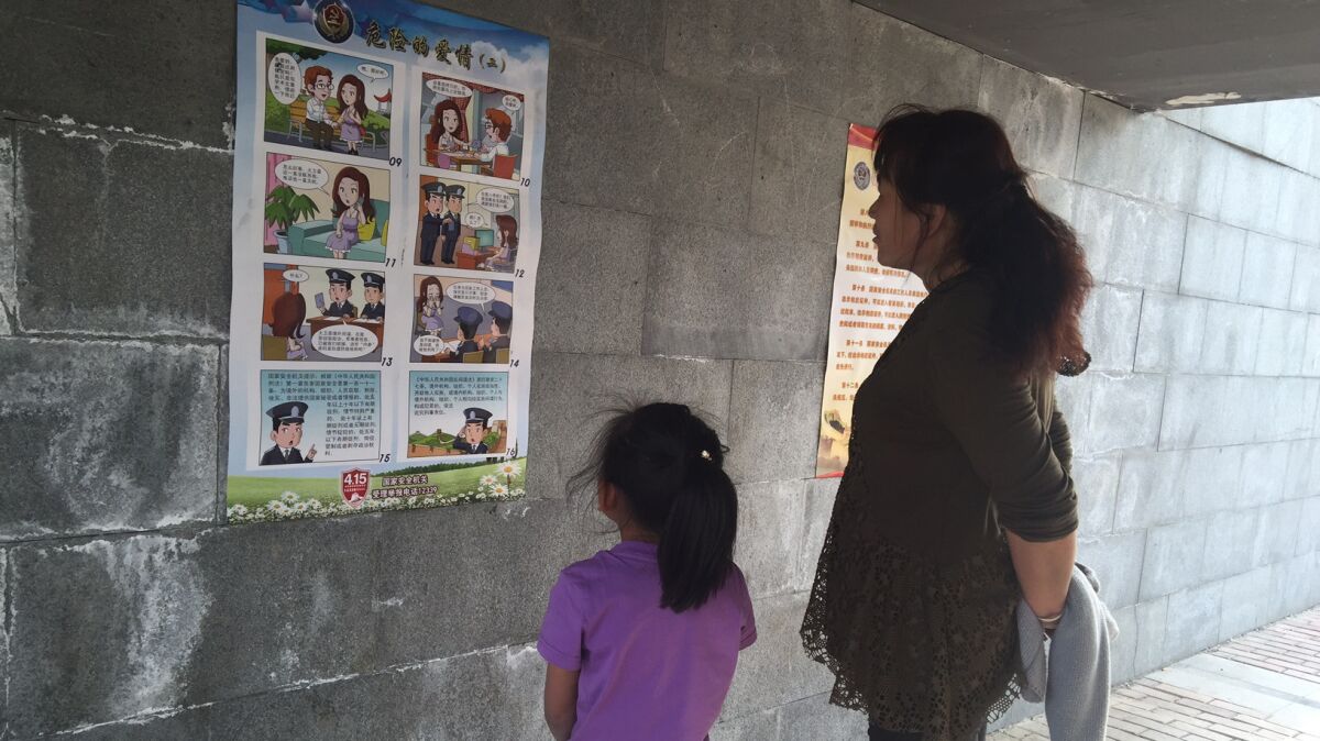 A mother and daughter look at a poster warning against foreign spies displayed at a riverside park in Beijing in April 2016.