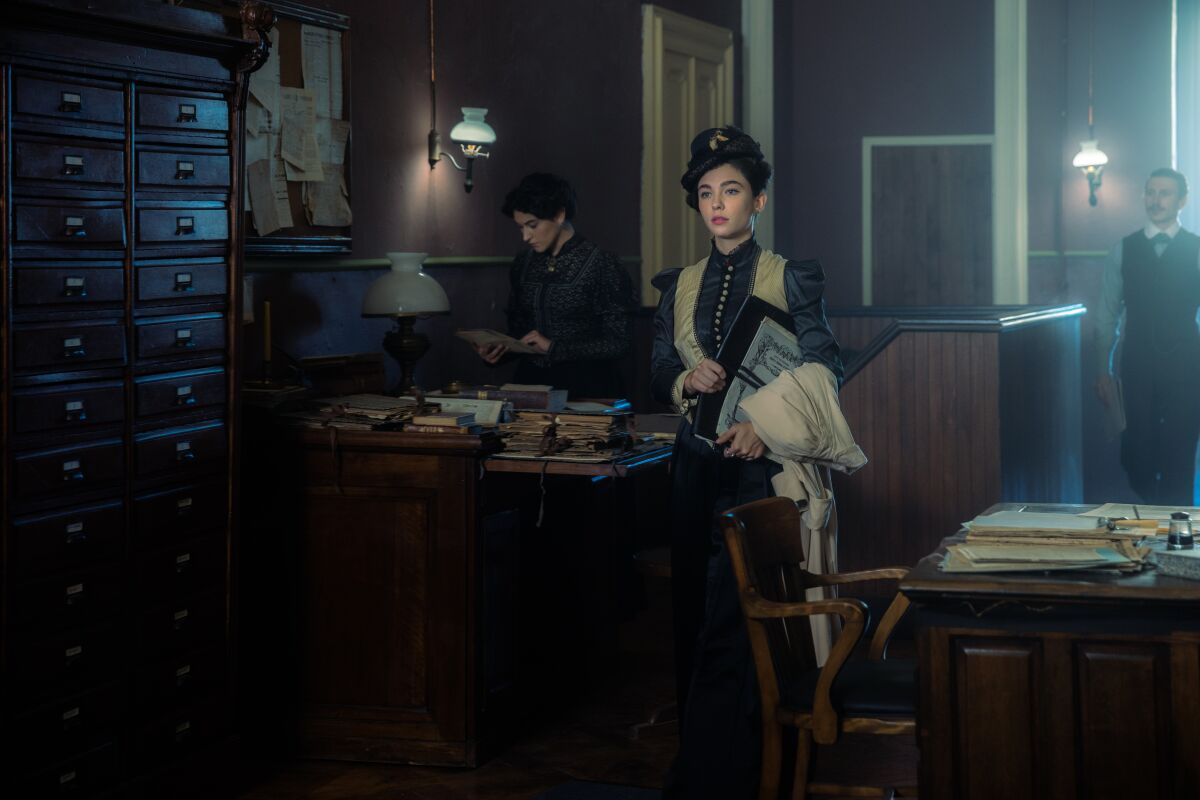 A woman standing in an office in turn of the century Turin.