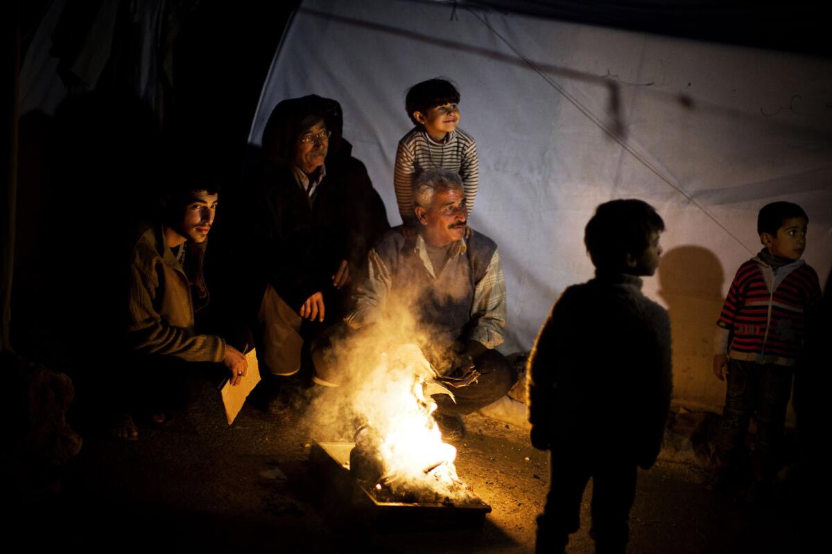 Syrian men make a fire to boil water Sunday near their tent at a refugee camp near the Turkish border in Azaz, Syria.