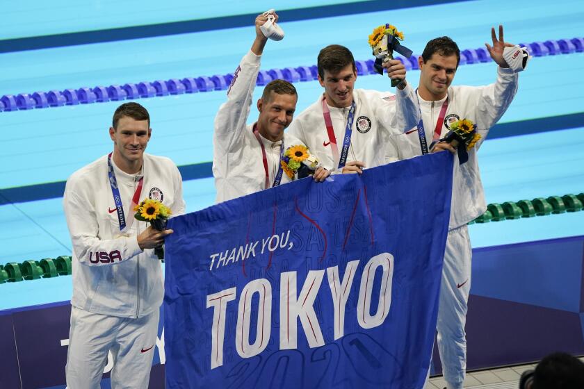 FILE - In this Aug. 1, 2021, file photo, members of the U.S. men's 4x100-meter medley relay team, Caeleb Dressel, Zach Apple, Ryan Murphy and Michael Andrew, carry a sign that reads, "Thank you, Tokyo" after winning the gold medal at the 2020 Summer Olympics, in Tokyo, Japan. (AP Photo/Jae C. Hong, File)