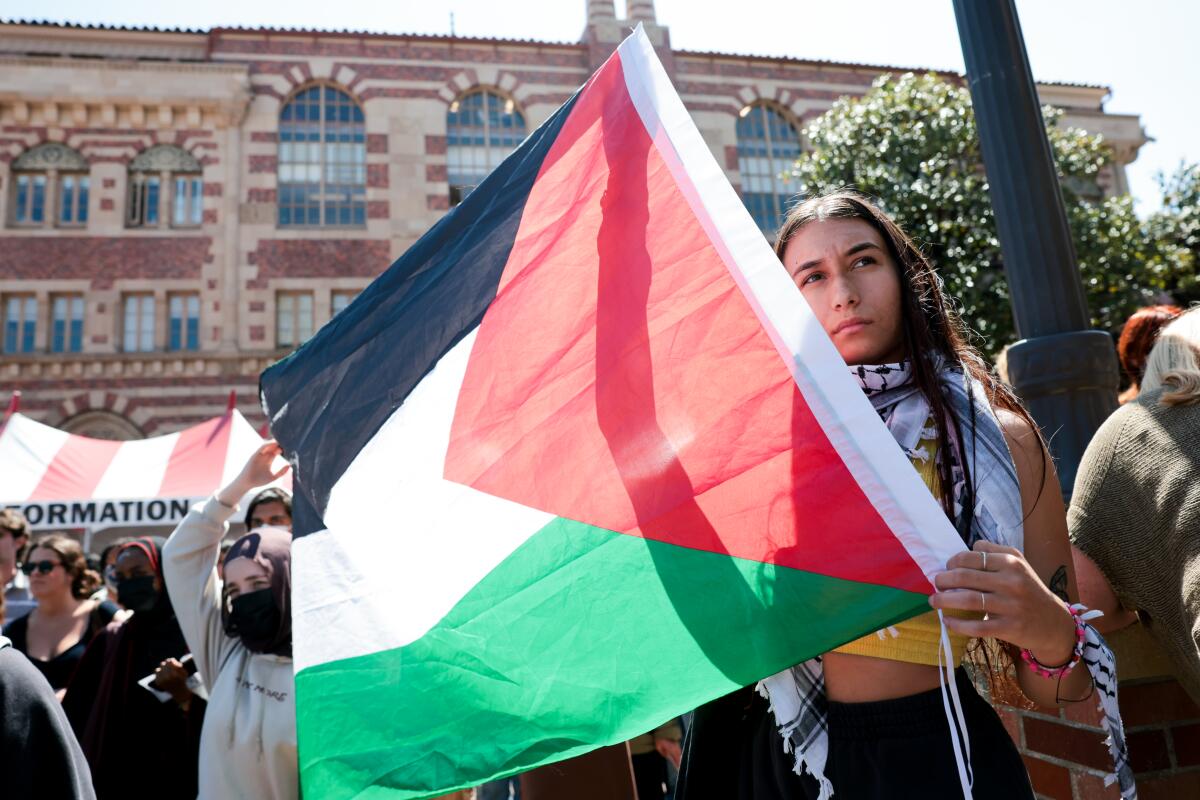 A student holds up a Palestinian flag during a silent march in support of Asna Tabassum
