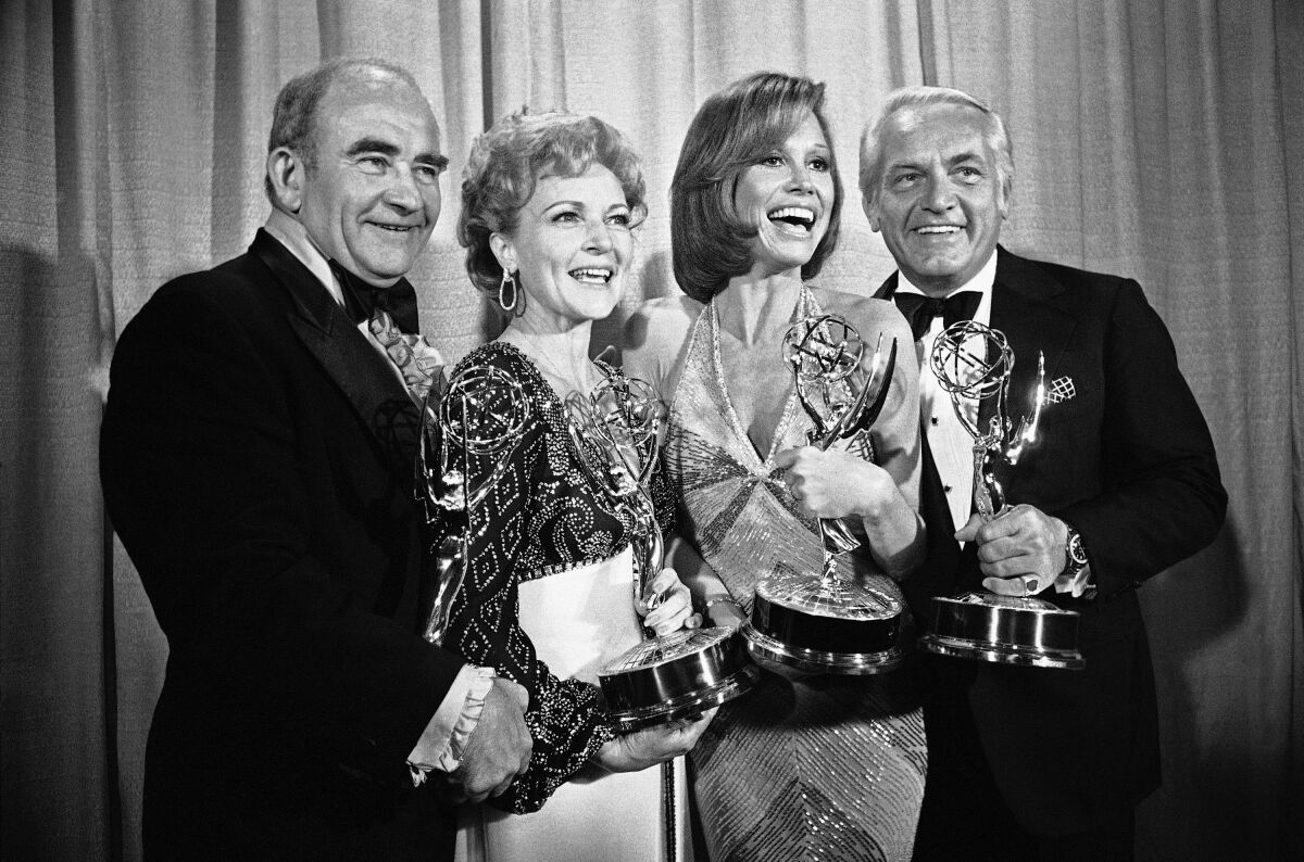 Two men and two women hold Emmy statuettes 