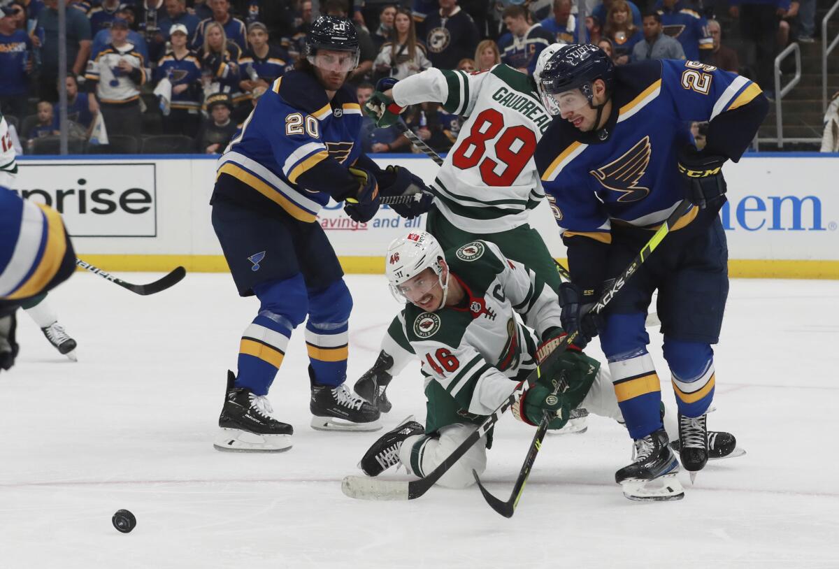 St. Louis Blues' Jordan Kyrou (25) and Minnesota Wild's Jared Spurgeon (46) vie for the puck during the second period in Game 6 of an NHL hockey Stanley Cup first-round playoff series Thursday, May 12, 2022, in St. Louis. (AP Photo/Michael Thomas)