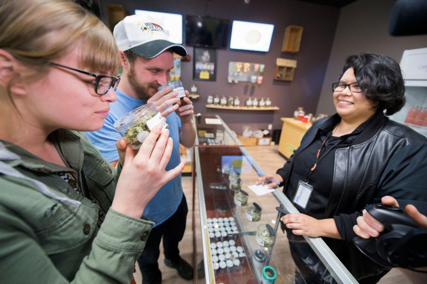 Tourists Laura Torgerson and Ryan Sheehan, visiting from Arizona, smell cannabis buds at the Green Pearl Organics dispensary on the first day of legal recreational marijuana sales in California, January 1, 2018 in Desert Hot Springs, California.