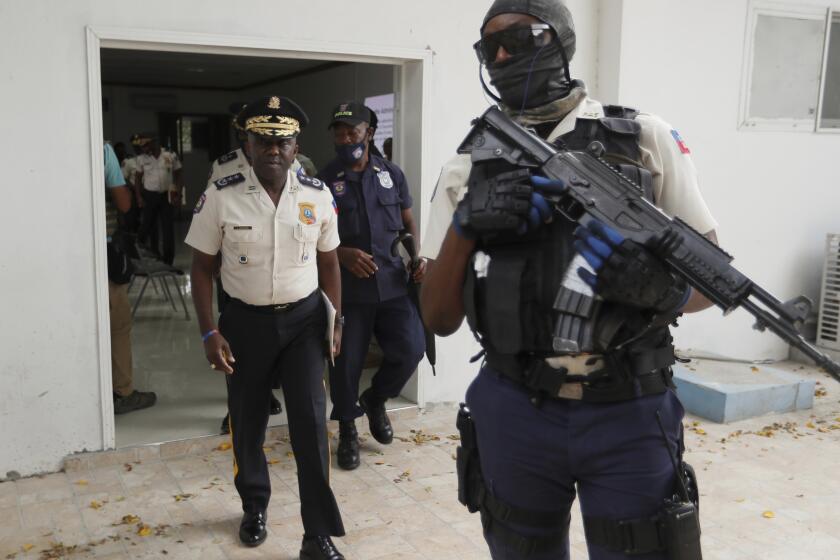 Leon Charles, left, Director General of Haiti's Police leaves a room after a news conference at police headquarters in Port-au-Prince, Wednesday, July 14, 2021. Charles gave an updated on the investigation of the July 7 assassination of President Jovenel Moise. (AP Photo/Fernando Llano)
