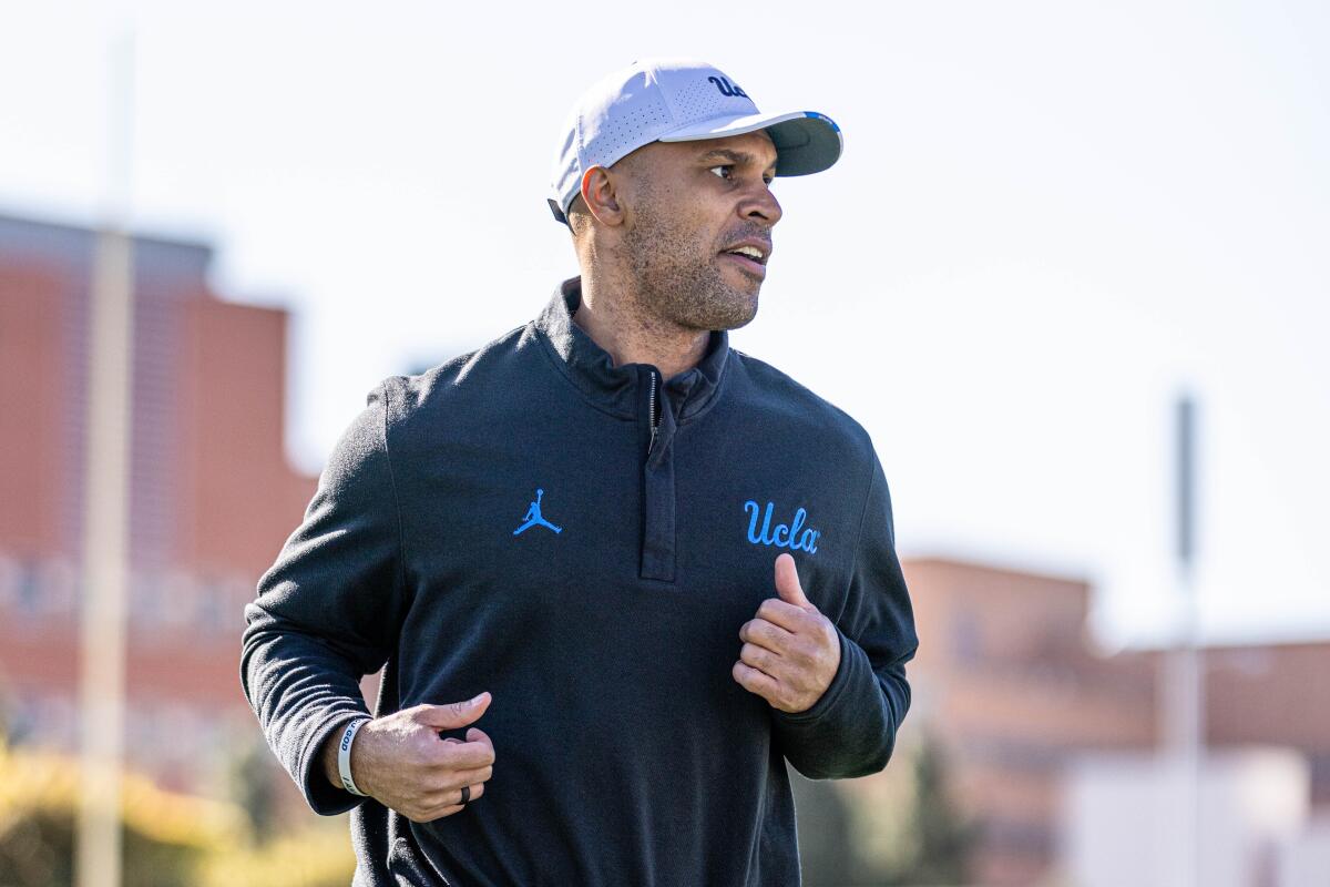 UCLA defensive coordinator D'Anton Lynn jogs on a field.