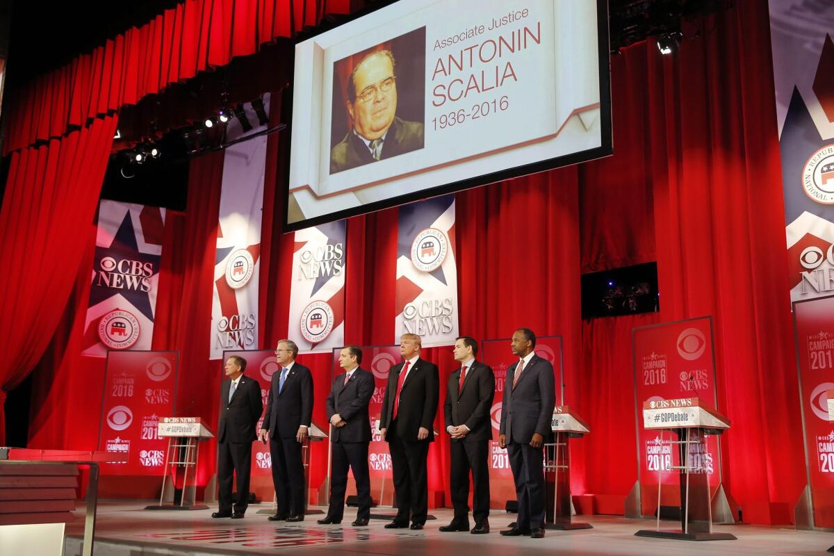 John Kasich, Jeb Bush, Ted Cruz, Donald Trump, Marco Rubio and Ben Carson take the stage beneath an image of U.S. Supreme Court Justice Antonin Scalia, who died earlier in the day.