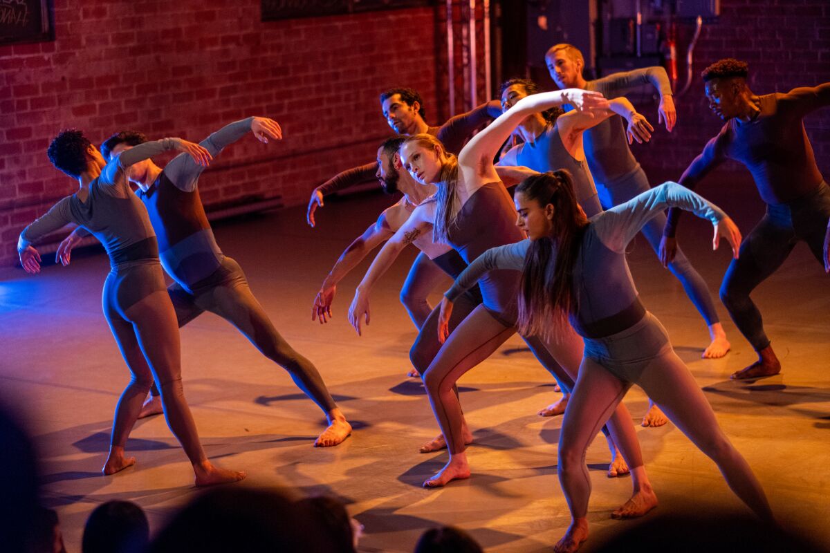 Dancers perform a move amid blue lighting.