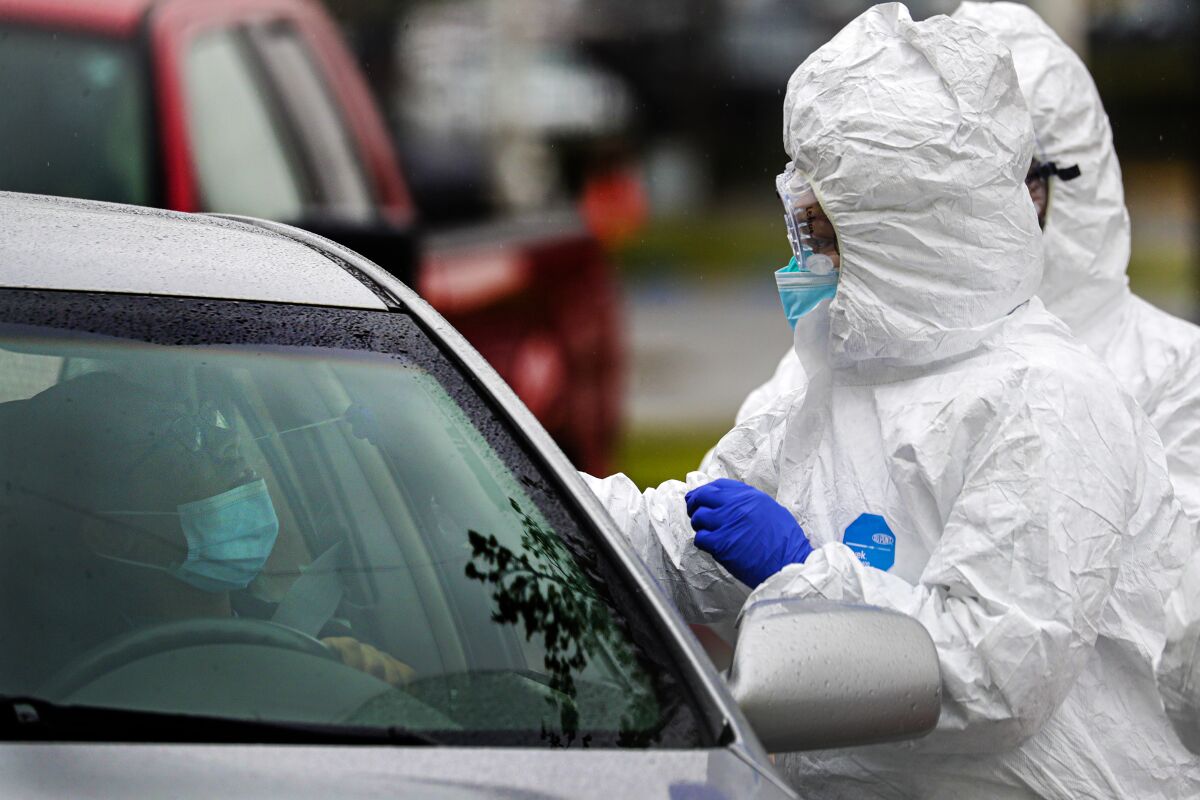 Alejandra Ortiz, left, sits in her car on April 9 as a nurse administers a coronavirus test at an Arrowhead Regional Medical Center public testing drive-through in Colton, San Bernardino County